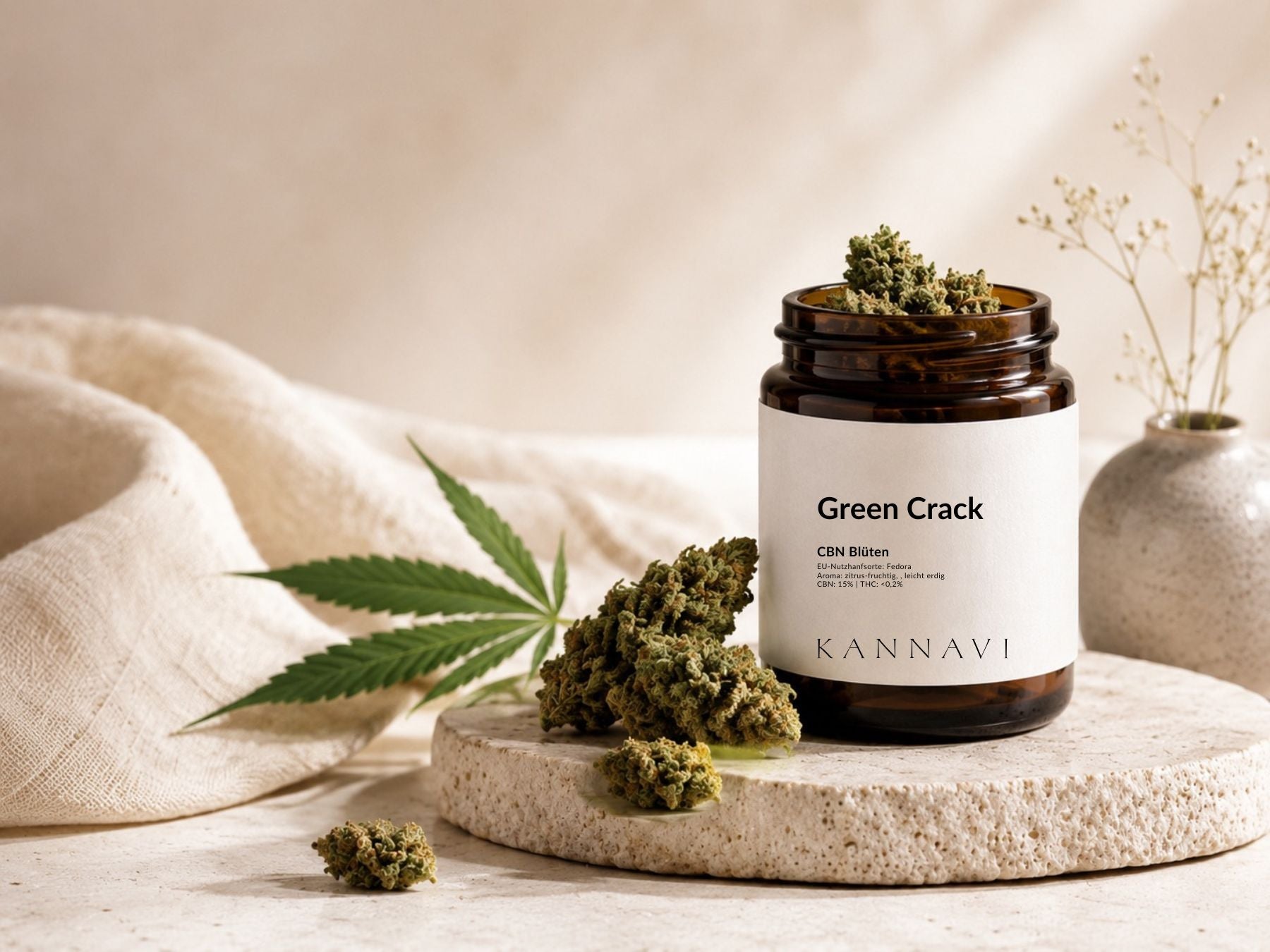 Kannavi Green Crack CBN Blüten im braunen Glas mit Hanfblüten und Hanfblatt auf heller Natursteinplatte
