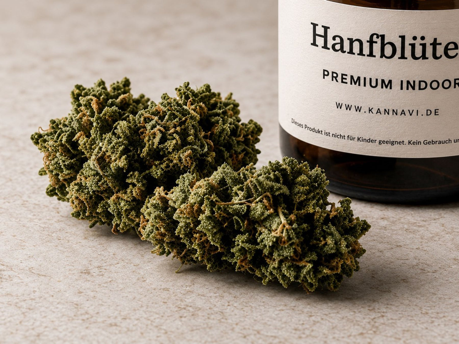 Hanfblüten neben braunem Kannavi Glas mit Etikett „Hanfblüte Premium Indoor“ auf hellem Naturstein